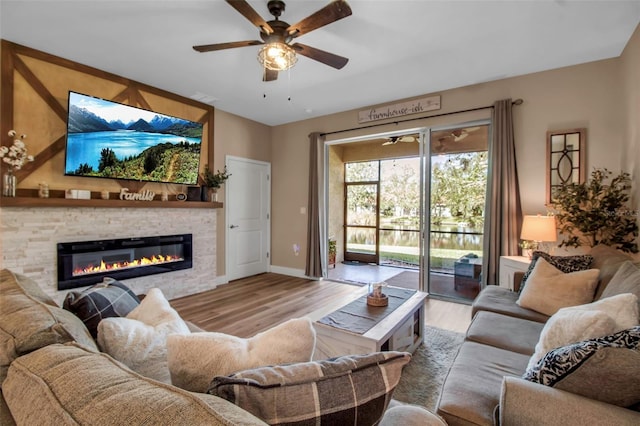 living room with ceiling fan, a fireplace, and light hardwood / wood-style floors