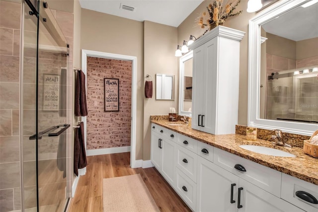 bathroom with wood-type flooring, walk in shower, and vanity