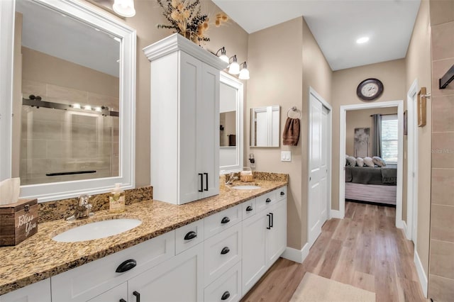 bathroom featuring hardwood / wood-style floors, vanity, and a shower with door