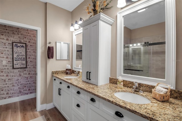 bathroom with hardwood / wood-style flooring, a shower with shower door, and vanity