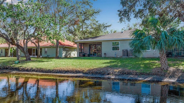 back of house featuring a lawn and a water view