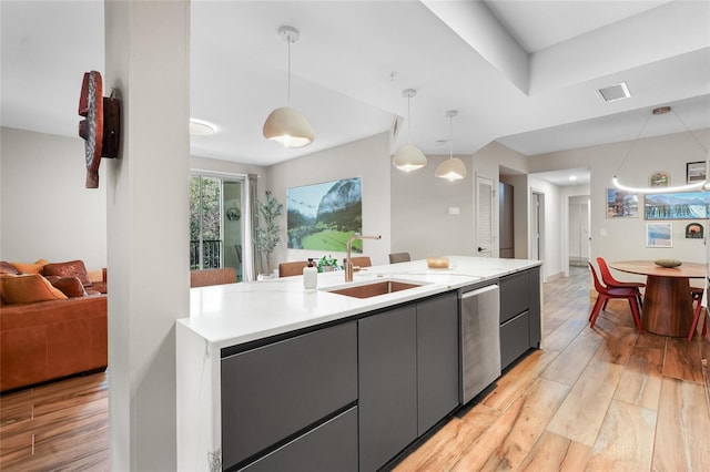 kitchen with stainless steel dishwasher, sink, hanging light fixtures, and light hardwood / wood-style flooring