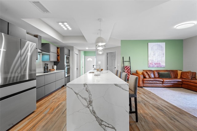 dining space featuring a raised ceiling, light wood-type flooring, and sink