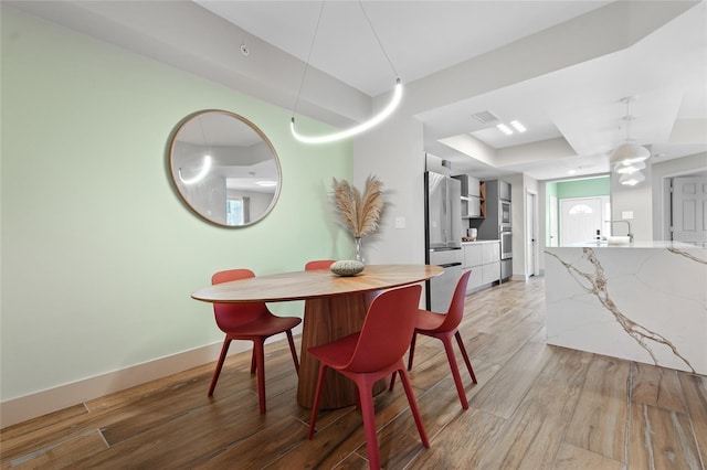 dining room with a raised ceiling and light hardwood / wood-style floors