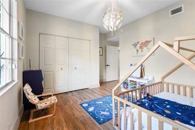 bedroom featuring a chandelier, wood-type flooring, and a closet