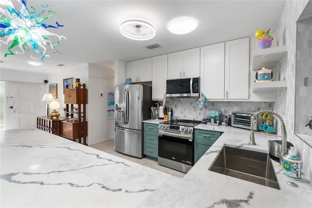 kitchen featuring sink, light stone countertops, appliances with stainless steel finishes, tasteful backsplash, and white cabinetry