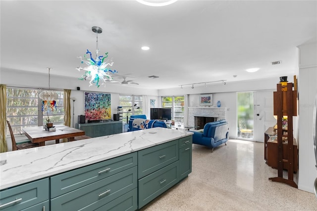 kitchen with plenty of natural light, ceiling fan, light stone countertops, and decorative light fixtures