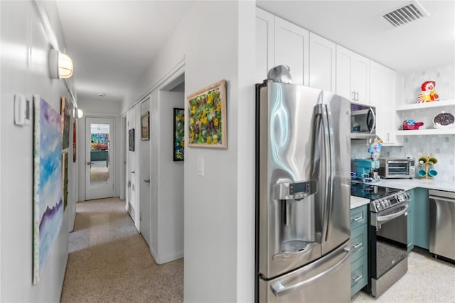 kitchen featuring white cabinets, backsplash, and stainless steel appliances