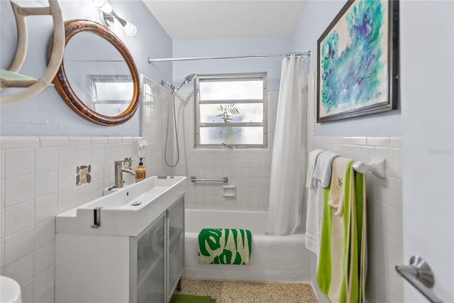 bathroom featuring vanity, shower / bath combo with shower curtain, and tile walls