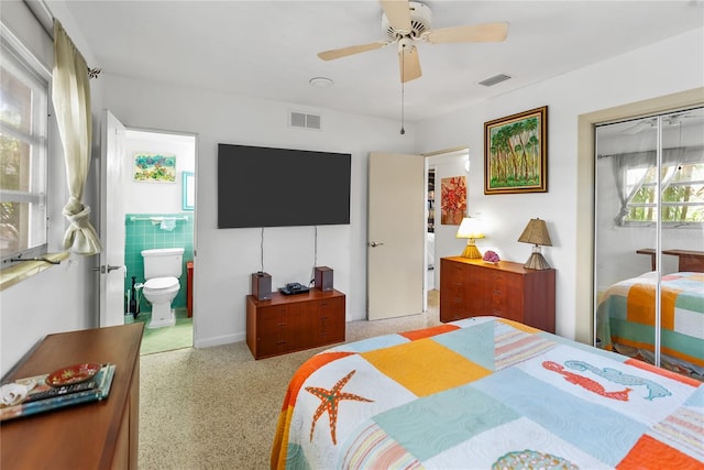 bedroom with ceiling fan, a closet, ensuite bathroom, and tile walls