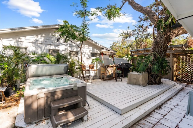 wooden deck with a covered hot tub and a grill