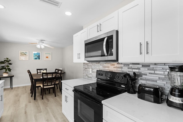 kitchen featuring backsplash, ceiling fan, black electric range, light hardwood / wood-style floors, and white cabinetry