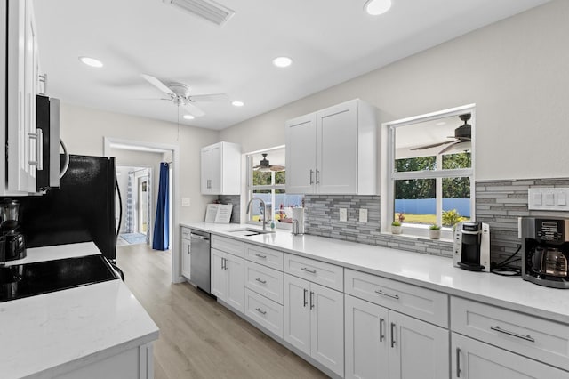 kitchen featuring plenty of natural light, white cabinets, black appliances, and sink