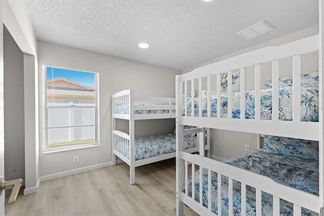 bedroom with a textured ceiling and light wood-type flooring