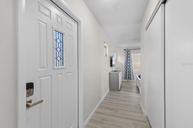 hallway with a textured ceiling and light hardwood / wood-style flooring