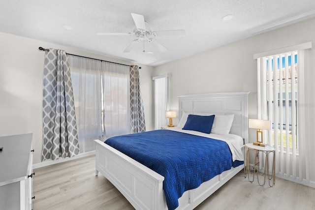 bedroom with a textured ceiling, light wood-type flooring, and ceiling fan