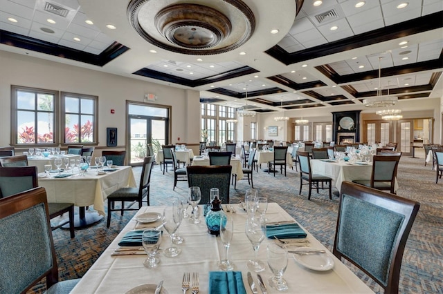 dining space featuring beamed ceiling, a towering ceiling, french doors, coffered ceiling, and a chandelier