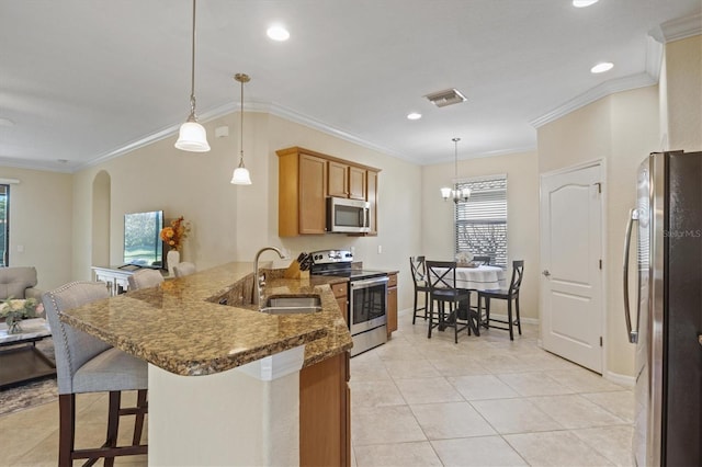 kitchen featuring kitchen peninsula, stainless steel appliances, decorative light fixtures, and sink