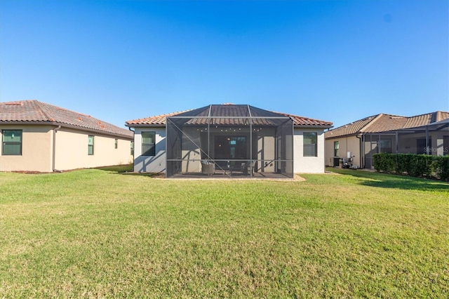 rear view of house featuring a lawn, glass enclosure, and a patio