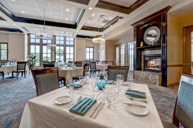 carpeted dining space featuring beam ceiling, coffered ceiling, a towering ceiling, and a fireplace