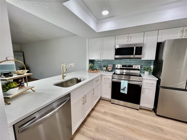 kitchen with white cabinets, sink, stainless steel appliances, and tasteful backsplash