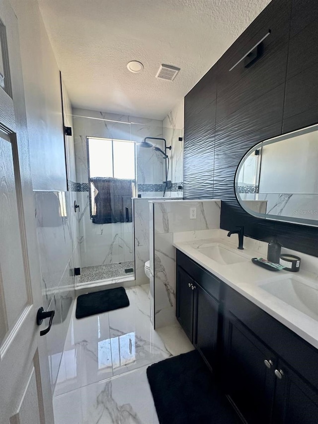 bathroom featuring vanity, toilet, a shower with shower door, and a textured ceiling