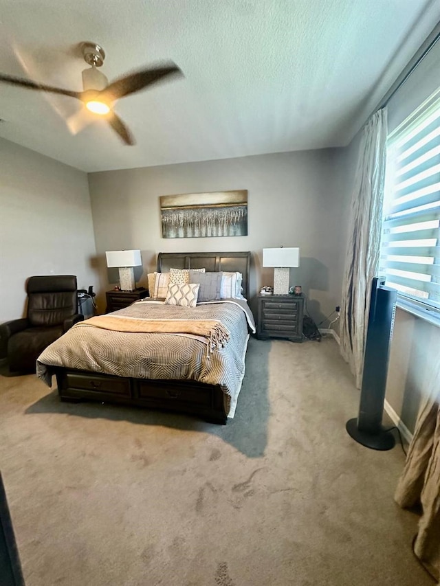 carpeted bedroom featuring ceiling fan and a textured ceiling