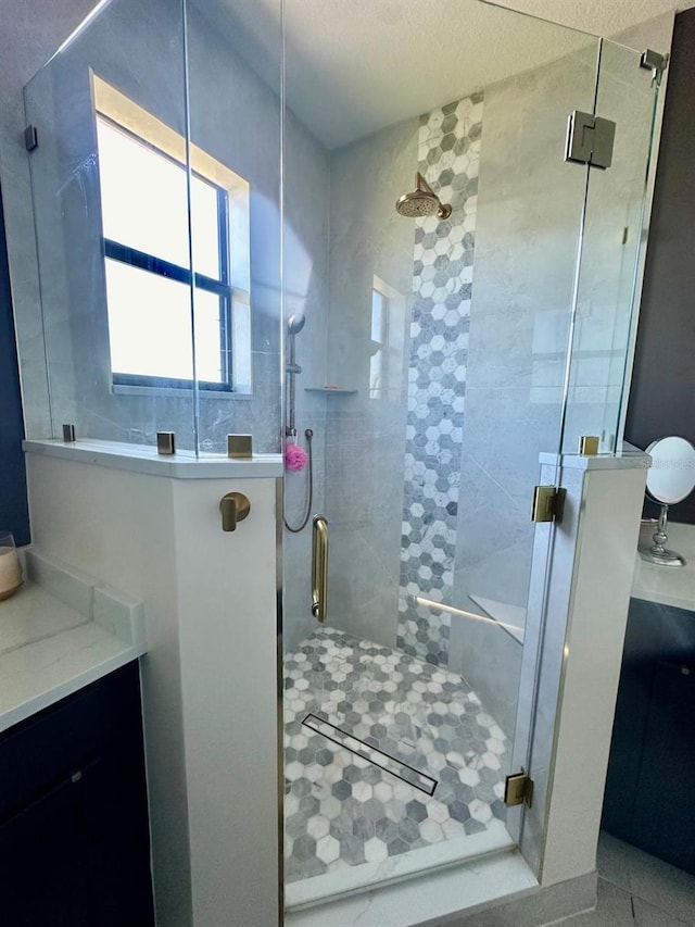 bathroom featuring tile patterned floors, vanity, a shower with door, and a textured ceiling