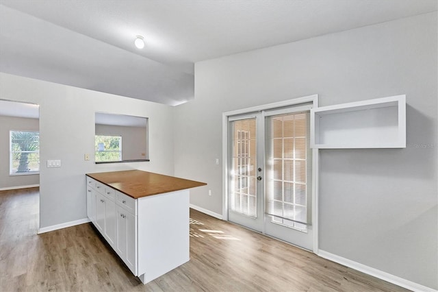 kitchen with wooden counters, french doors, light hardwood / wood-style floors, white cabinetry, and lofted ceiling