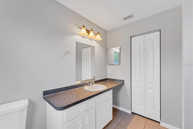 bathroom with tile patterned flooring, vanity, and toilet