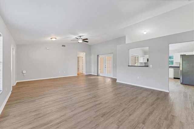 unfurnished living room featuring french doors, ceiling fan, light hardwood / wood-style flooring, and vaulted ceiling