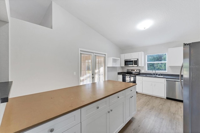 kitchen featuring appliances with stainless steel finishes, light wood-type flooring, french doors, sink, and white cabinetry