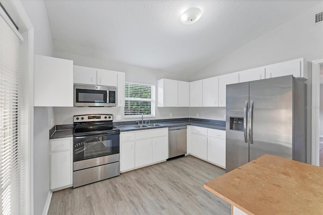 kitchen featuring lofted ceiling, sink, a textured ceiling, white cabinetry, and stainless steel appliances