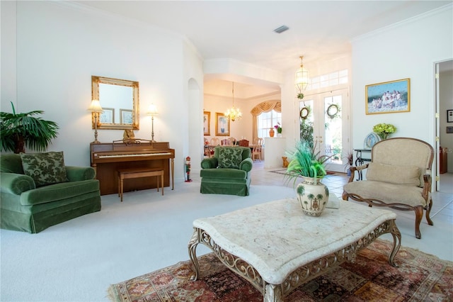 sitting room featuring carpet flooring, crown molding, french doors, and a notable chandelier