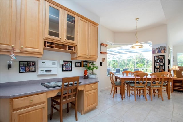 kitchen featuring light brown cabinets, built in desk, decorative light fixtures, and light tile patterned floors