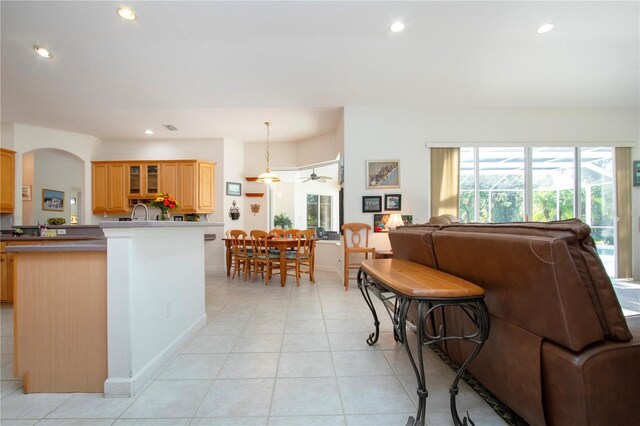 kitchen with ceiling fan, kitchen peninsula, hanging light fixtures, and light tile patterned floors