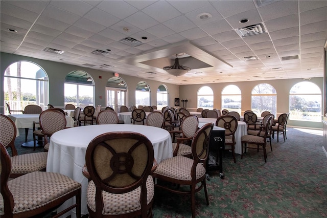 carpeted dining area featuring a paneled ceiling