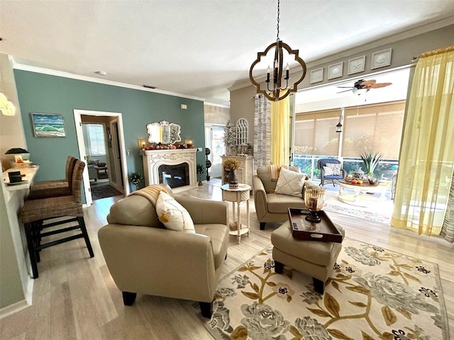 living room featuring crown molding, ceiling fan with notable chandelier, and light wood-type flooring