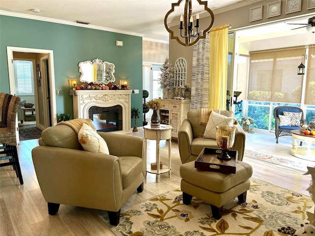 living area with light hardwood / wood-style flooring, ceiling fan with notable chandelier, and ornamental molding