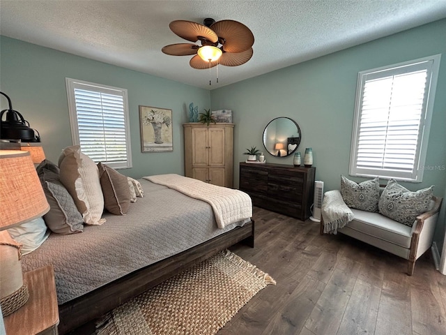 bedroom with ceiling fan, dark hardwood / wood-style floors, and a textured ceiling