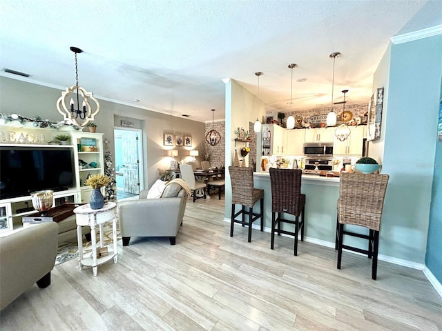 living room with ornamental molding, a textured ceiling, light hardwood / wood-style floors, and a notable chandelier