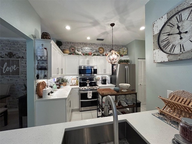 kitchen featuring decorative backsplash, stainless steel appliances, sink, decorative light fixtures, and white cabinetry