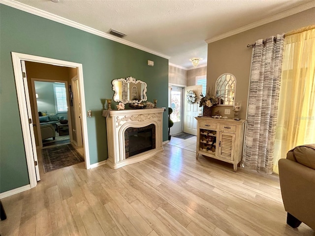 living room with ornamental molding, a textured ceiling, and light wood-type flooring