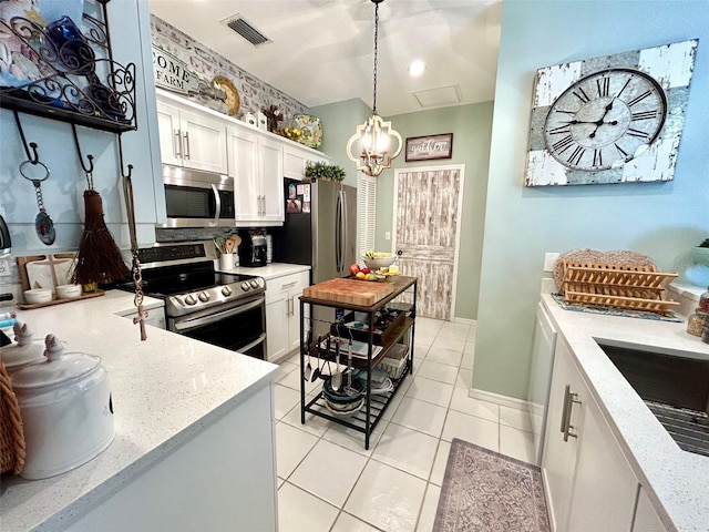 kitchen with hanging light fixtures, stainless steel appliances, white cabinets, light stone counters, and light tile patterned flooring