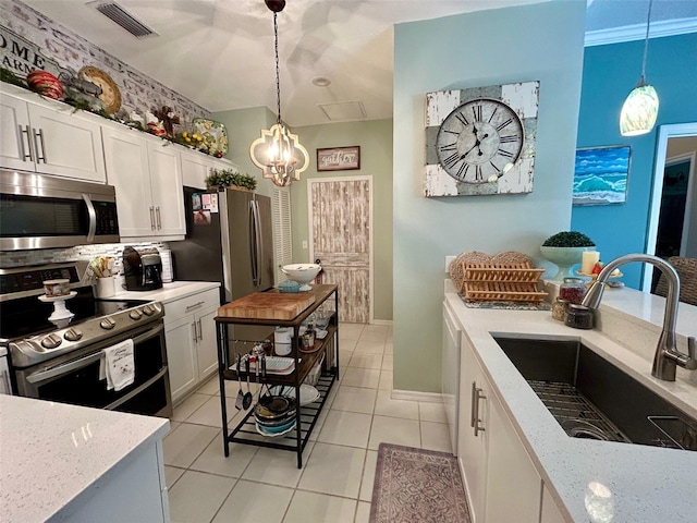 kitchen with light stone countertops, stainless steel appliances, sink, pendant lighting, and white cabinetry