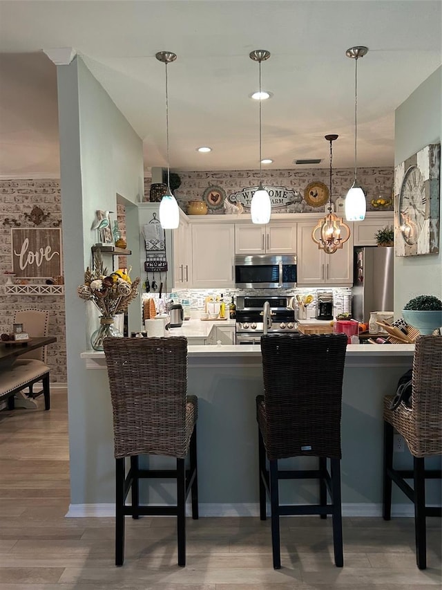 kitchen featuring hanging light fixtures, tasteful backsplash, appliances with stainless steel finishes, and a breakfast bar area