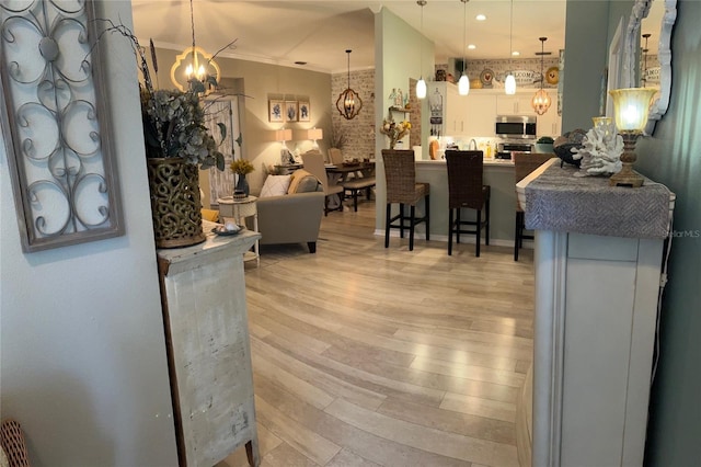 interior space with ornamental molding, a notable chandelier, and light wood-style flooring