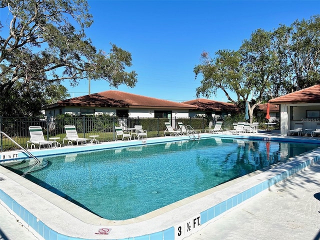 community pool with a patio and fence