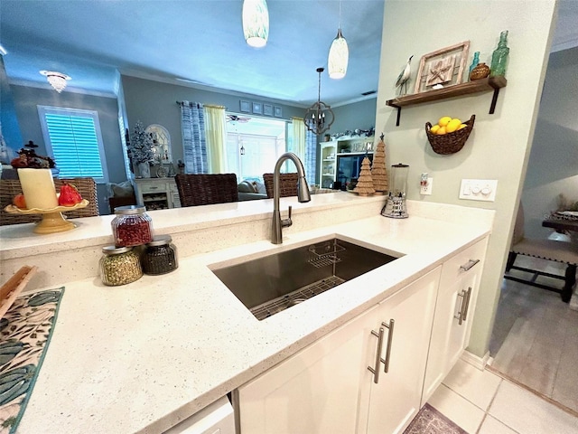 kitchen with ornamental molding, a sink, white cabinetry, and a healthy amount of sunlight