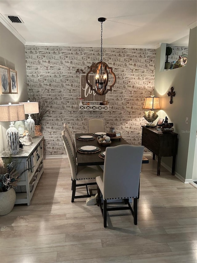 dining area with visible vents, crown molding, brick wall, and wood finished floors